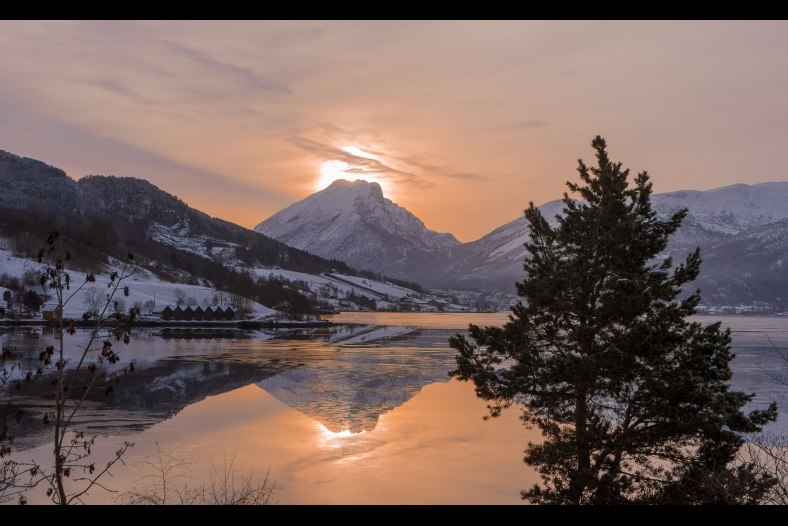 Winter morning. Thin, high haze on the sky and patches of ice on a calm fjord. The mountain Ryssdalshorn - Norway